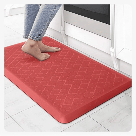 Red anti-fatigue floor mat providing a cushioned standing surface for kitchen work areas