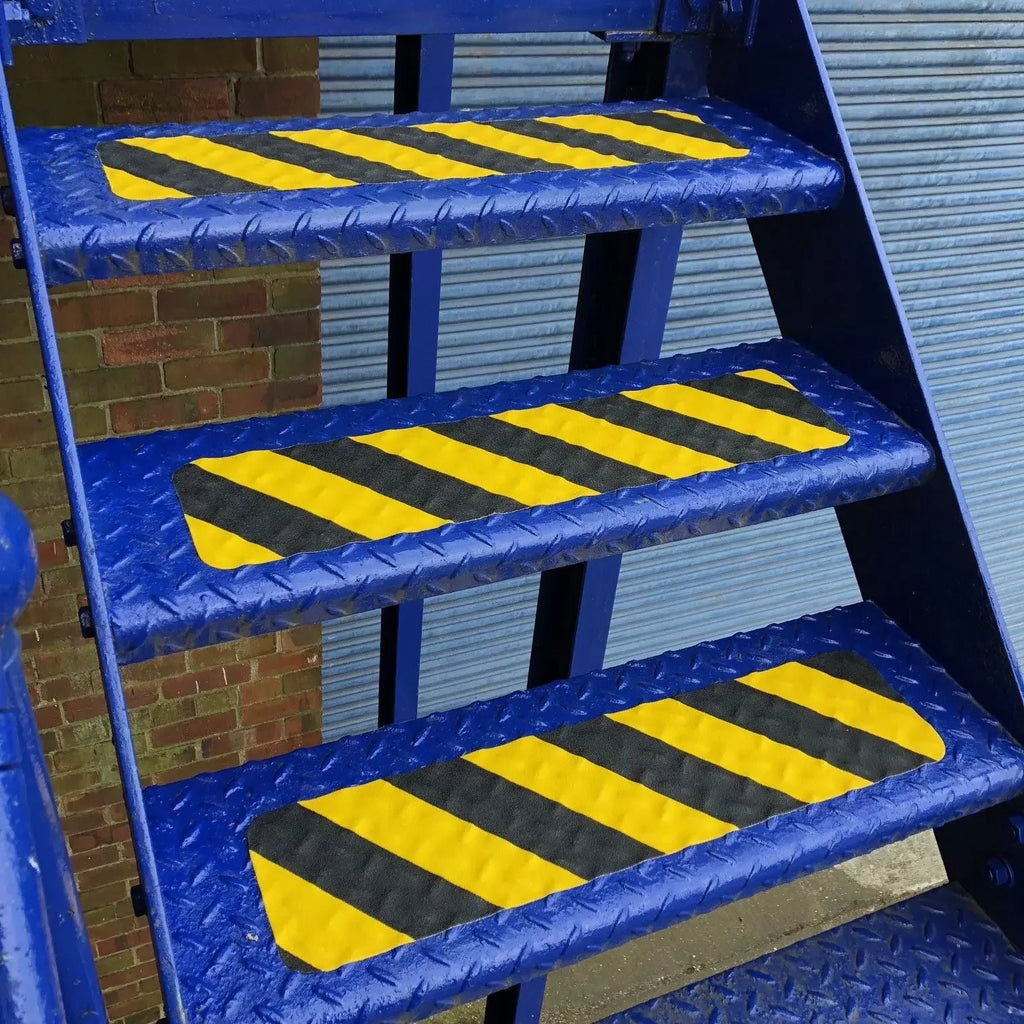 Yellow and black anti-skid safety tape strips installed on industrial metal stairs