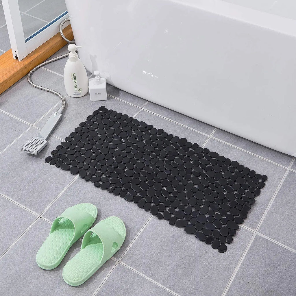 LifeKrafts black stone pebble anti-slip bath mat beside bathtub on tiled floor