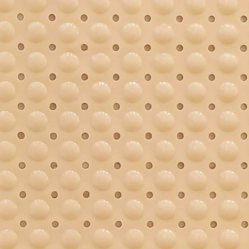 Close-up of cream Soft Pebble bath mat showing raised textured surface and drainage holes