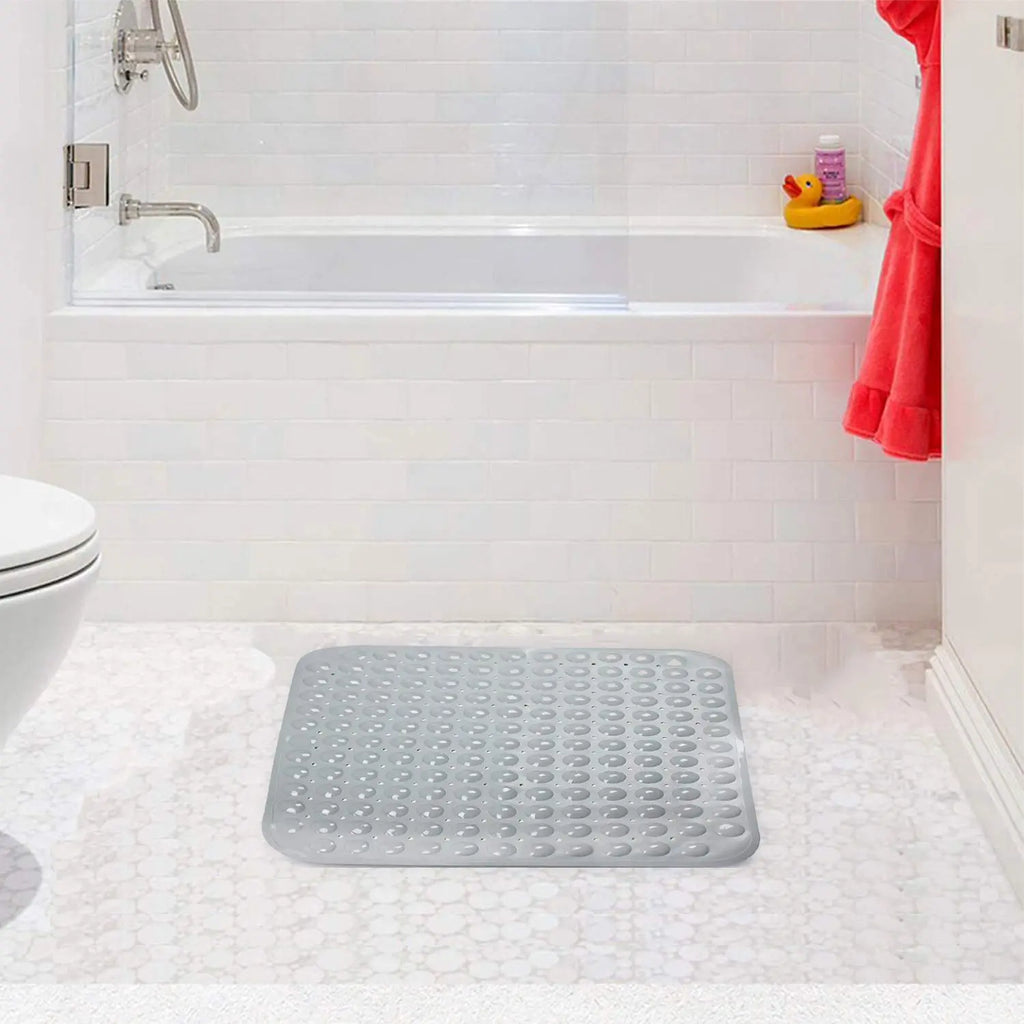 Grey soft pebble anti-slip bath mat on bathroom floor near bathtub