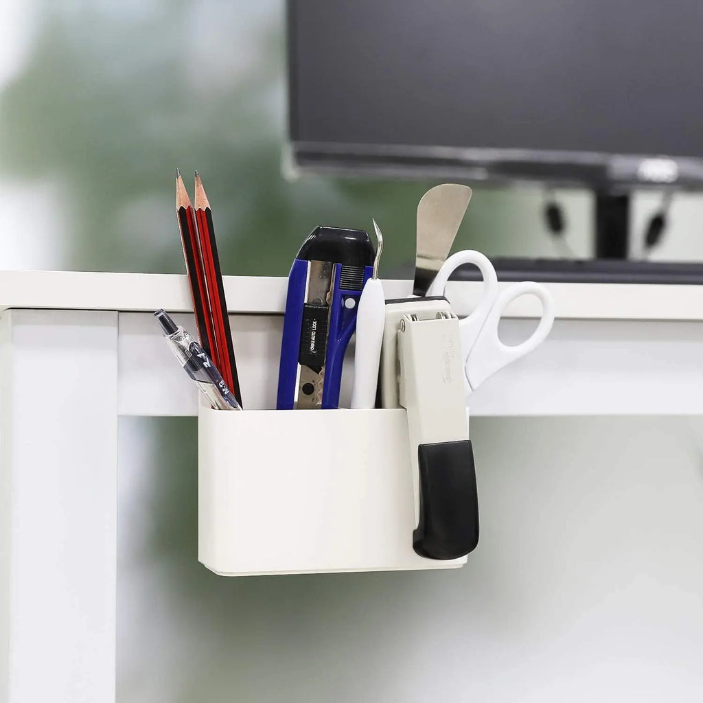 White magnetic pen and pencil holder organizing office supplies on a metal surface