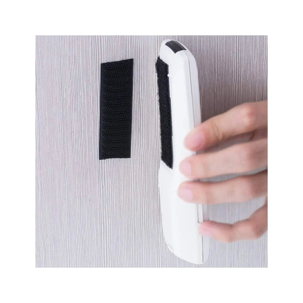 Self-adhesive black hook and loop tape securing a lightweight item to a wall